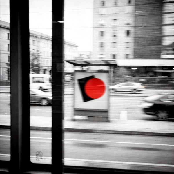 Manifesto con un cerchio rosso visto dal finestrino di un tram in corsa, città in bianco e nero mossa
